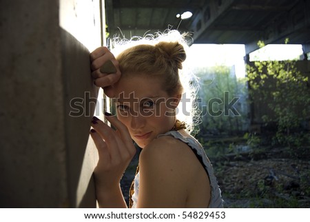 Young woman wearing blue dress posing outdoors at industrial zone