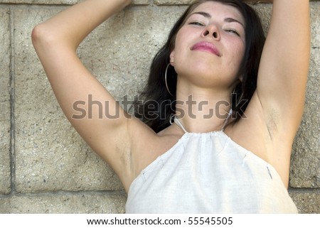 Young attractive woman against aged stone wall.