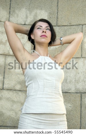 Young attractive woman against aged stone wall.