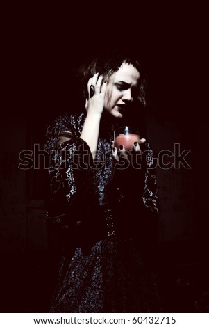 Young emotional gothic woman hanging candle in empty grunge dark room