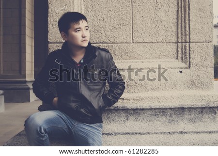 Portrait of a modern handsome asian man against vintage wall of old building
