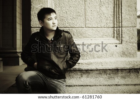 Dramatic portrait of young asian man against vintage building wall