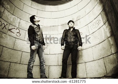 Dramatic portrait of two young asian men against vintage building wall
