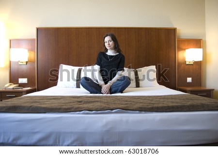 Young woman on bed in hotel room with nice interior design