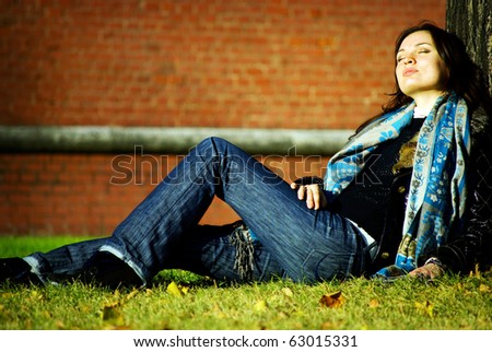 Attractive brunette lady sitting near a tree