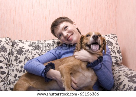 Young woman playing with her dog on sofa in her apartment