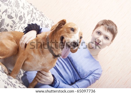 Young woman playing on a sofa with her joyful dog
