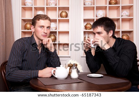 Two smiling business men speaking about deal at restaurant on lunch break