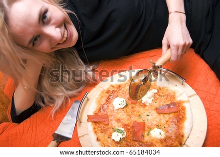Portrait of young woman eating fresh hot pizza at her home laying on bed