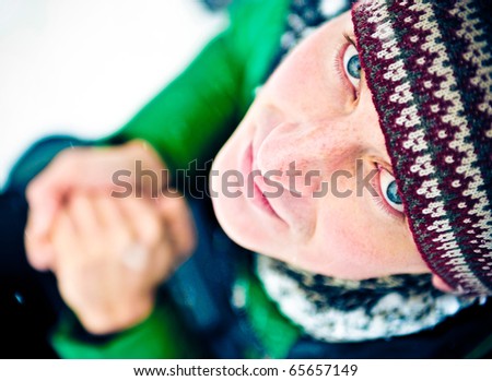 Portrait of young cheerful man outdoor in winter park warming his hands and dreaming about summer
