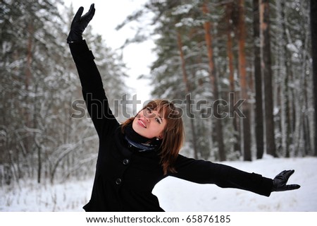 Outdoor portrait of young beautiful european style woman - standing in winter forest with opened arms. Success and luck concept