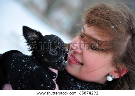 Outdoor portrait of young beautiful european style woman - holding her little dog in her arms and warming it. Care and liability concept