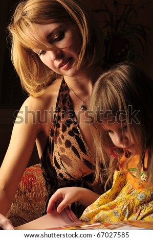 Low key portrait of young mother reading a book for her child .