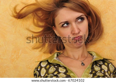 Young disappointed woman looking aside portrait standing against orange wall