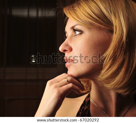 Portrait of a calm young woman sitting inside dark room with romantic light