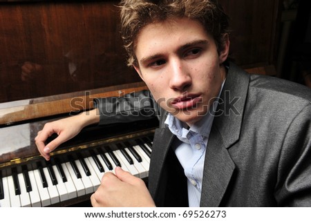 Portrait of young man indoor at his apartment in evening playing piano