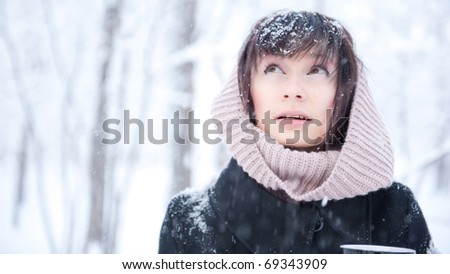 Poster portrait of young woman outdoor in winter park enjoying warming drink
