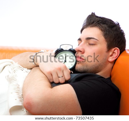 Young sleeping man and alarm clock in bedroom at home
