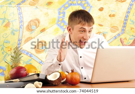 Portrait of handsome relaxed office worker at his desk under umbrella at beach and with different fruits on his table. Crediting people, giving opportunities and making dreams come true concept.