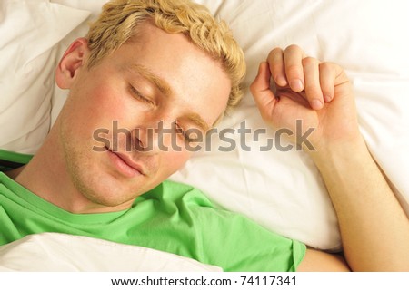 Attractive man relaxing in bed. White silk linen
