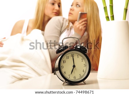 Two women in a bed. Wake up in morning. Alarm at front