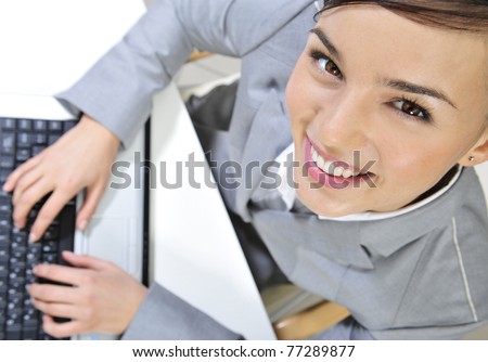 Beautiful happy and smiling business woman working on computer at her office looking up at the camera