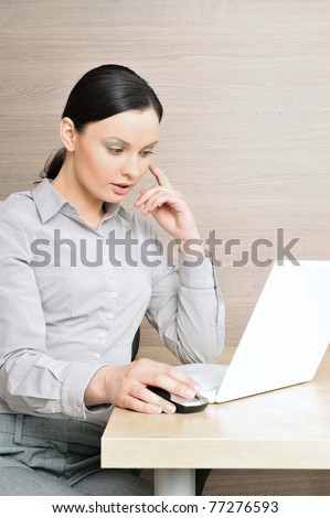 Portrait of a beautiful young businesswoman on the computer, touching her head. Office background.