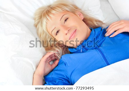 Closeup portrait of beautiful young blond woman on the bed at home