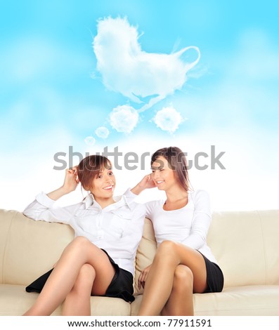 Portrait of two young pretty girls sitting relaxed on sofa and talking about motherhood
