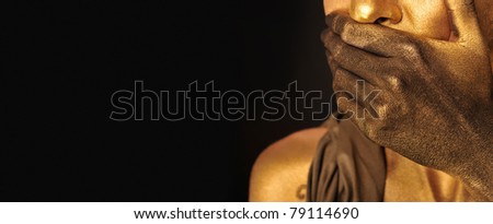 Portrait of young sexy woman in golden paint against dark background. Fuel crisis concept