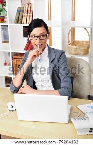 Beautiful business woman wearing eye glasses thinking about something while working on computer at her office
