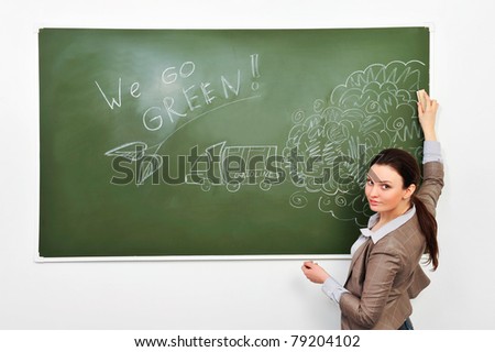 Closeup portrait of young pretty woman wearing formal suit erasing gasoline smoke on green board. Ecology care concept