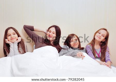 Portrait of happy family of only girls of different ages. Laying under covering at their bedroom
