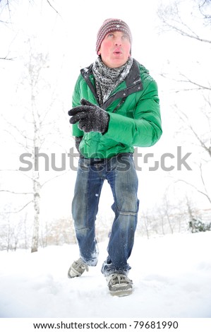 Closeup portrait of young man running in winter park wearing sportswear and looking forward