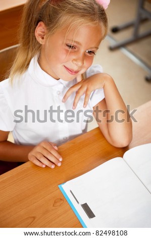 Image of smart child reading interesting book in classroom. Vertical Shot