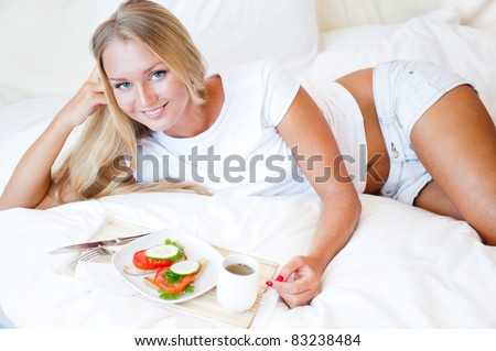 Woman having breakfast in bed. Healthy continental breakfast. Caucasian woman smiling looking at camera.