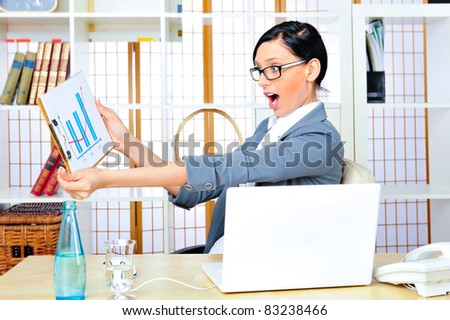 Beautiful business woman smiling while working with reports and statistics and using computer at her office