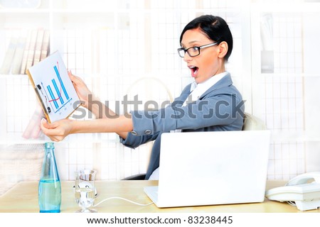 Beautiful business woman smiling while working with reports and statistics and using computer at her office