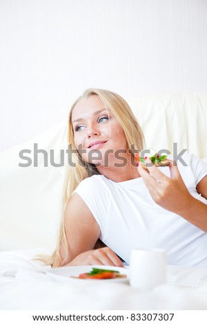 Woman having breakfast in bed. Healthy continental breakfast. Caucasian woman smiling looking away