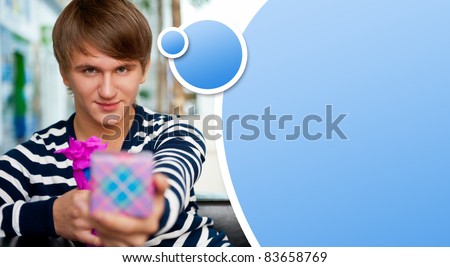 Portrait of young man inside shopping mall sitting relaxed on couch, holding box and preparing to make his couple a gift. Blank balloon with lots of copyspace for your text and logo
