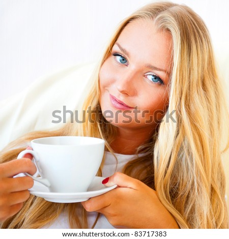 Young woman at home sipping tea or coffee from a cup