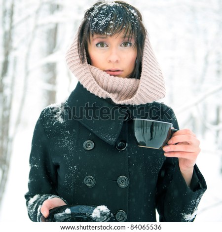 Portrait of young beautiful woman standing alone in winter park and drinking coffee. Take-away coffee as natural as it can be - concept. Advertisement banner