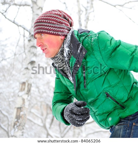 Closeup portrait of young man running in winter park wearing sportswear and looking forward