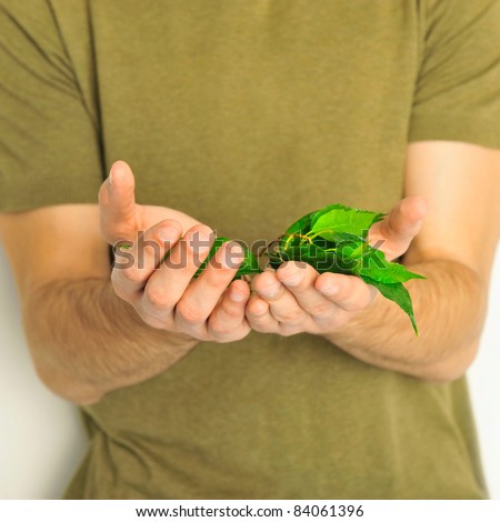 Young masculine healthy man holding plant in hands