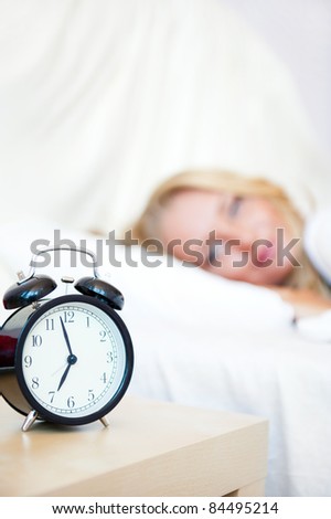 Woman sleeping in bed and alarm-clock (focus on alarm clock)