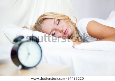Woman sleeping in bed and alarm-clock (focus on woman)