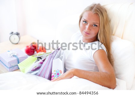 Young happy attractive girl unpack shopping bags in bedroom or hotel after enjoying being in mall. Horizontal Shot