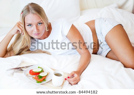 Woman having breakfast in bed. Healthy continental breakfast. Caucasian woman smiling looking at camera.
