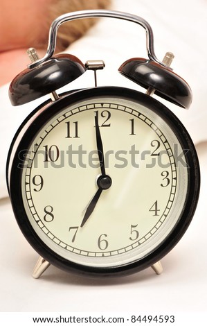 Closeup of beautiful retro style alarm clock inside bedroom. Sleeping woman on background
