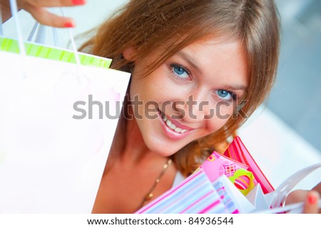 Happy shopping woman at the mall preparing gifts for her friends and relatives on christmas and boxing day. She is smiling and full of energy. Blank balloon with copyspace for your needs